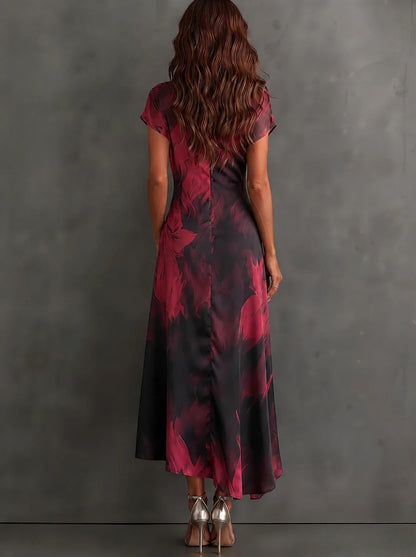 Sara - Vestido midi cruzado con estampado abstracto rojo y negro, cuello en V, manga corta, cinturón y bajo asimétrico con volantes.